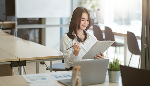 在会议室处理财务报告的成功年轻亚洲女商务人士的画像图片