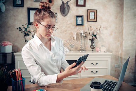 女企业家在办公桌前工作 同时使用计算器计算家庭办公室的营销财务 女商务人士在 Covid-19 大流行期间在家忙着工作图片