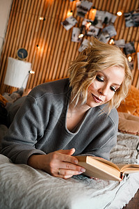 妇女在舒适的床上放松和阅读书装饰咖啡国家生态小屋长椅房子日志风格木头图片