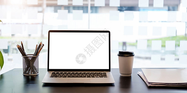 黑桌上有空白屏幕的笔记本电脑 上面有杯子和胡椒图片
