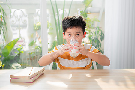 可爱男孩在做功课后坐在桌子上喝着牛奶的杯子家庭作业教育水果童年男生玻璃孩子学生课堂学校图片