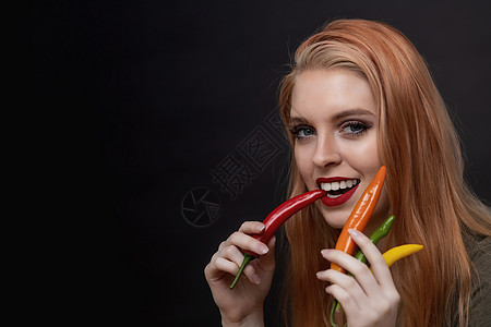 迷人的年轻女人正在尝红辣椒辣椒图片
