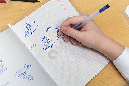 女孩手拿一支带蓝墨水的喷泉笔 能解决数学方面的例子笔记本班级学习男生教训蓝色知识孩子课堂考试图片