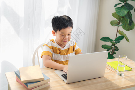 网络教育和电子学习概念 在家中微笑与有趣的面孔研究笔记本电脑的亚洲前童子弟学生技术互联网男生家庭作业孩子学校写作图片