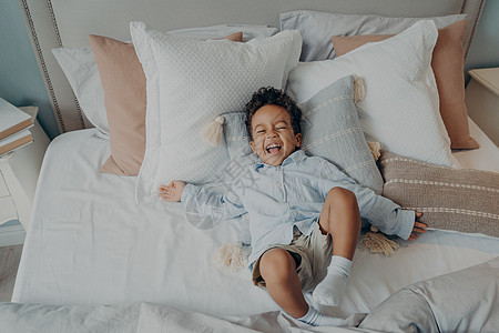 躺在床上笑笑笑的枕头上的美国快乐小男孩的肖像图片
