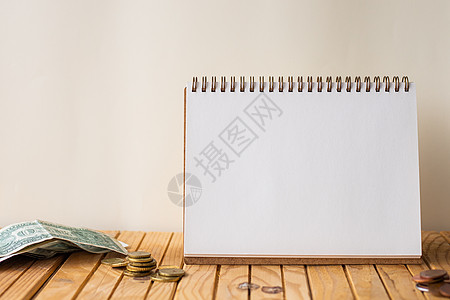 在桌子顶部的硬币堆旁边清空打开的螺旋笔记本 木桌上放着成堆硬币的空白打开日记本图片