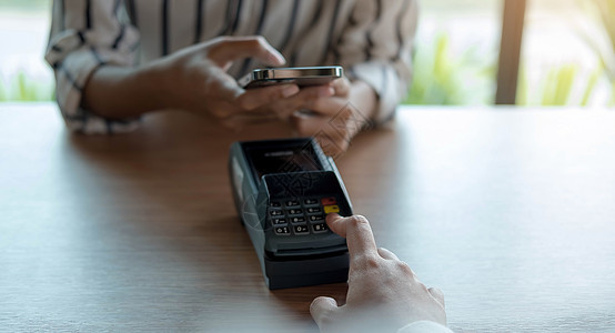 女人在咖啡中使用 NFC 技术通过智能手机支付账单 客户使用非接触式技术通过手机付款 咖啡店移动支付的特写手店铺零售服务读者出纳图片