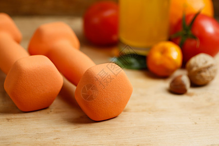 木制桌上的脑铃 橙汁 水果和坚果 体育和健康生活方式概念图片