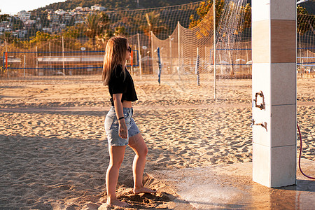 一个穿短裤的女孩 和一件黑色T恤 在海滩附近的淋浴女性热带排球头发女士天堂天空身体享受旅行图片