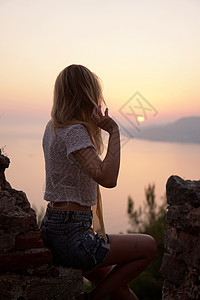 女孩从一个高点看海日落 垂直照片海浪天空阴影日落旅行空气女士岩石成人假期图片