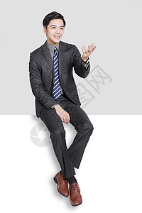 坐在空白面板上的青年商务人士男性姿势微笑商务工作办公室经理男人商业手势图片