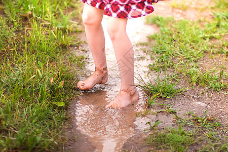 赤脚女孩在夏雨过后穿过水坑 走过一滩水童年树木女孩小姑娘飞溅喜悦花园赤脚假期幸福图片