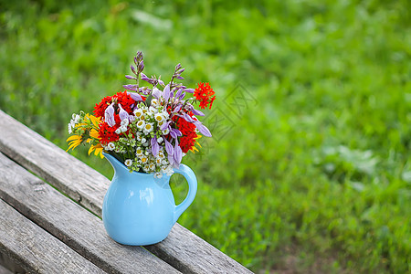 在木凳上的蓝色陶瓷花瓶里 盛满鲜花郁金香植物群桌子花束礼物玻璃玫瑰木头树叶团体图片