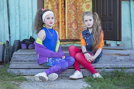两个风趣的小女孩 妆容鲜艳 穿着九十年代风格的衣服 坐在房子的乡村门廊上 俄罗斯乡村的孩子图片