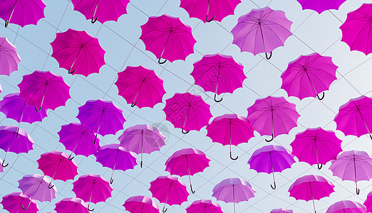 许多粉红色的雨伞挂在树上图片