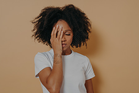 黑皮肤女性用手蒙面 对米壁感到焦虑或抑郁; 对蜜蜂墙表示忧虑或沮丧图片