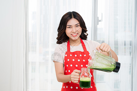 年轻的年青女性在家厨房做绿色解毒冰淇淋水果果汁食物排毒女孩饮料蔬菜奶昔营养机器图片