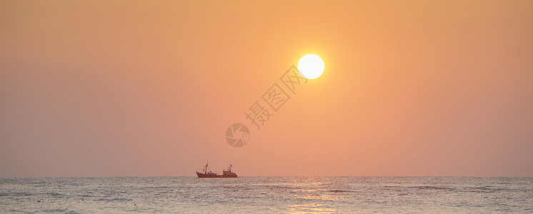 海边日落时橙色天空下渔船的休眠钓鱼橙子海浪太阳旅行海洋反射旅游海岸阳光图片