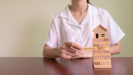 家庭保险和资产风险的概念 保险代理人用写有“INSURANCE”字样的木块来保护样板房图片