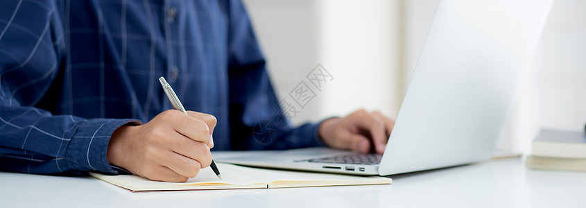 特写手的商务人士写在笔记上 同时在家里的办公桌上使用笔记本电脑 男性计划商业成功 作者和博客 在桌子上工作的商务人士 员工和工作图片