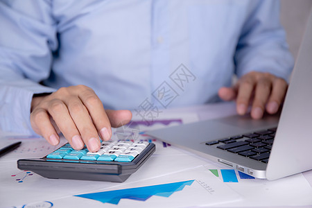 商务人士的手用计算器计算税款 而笔记本电脑放在办公桌上 用图形和图表 统计和检查账户 商业概念规划财务和投资预算文档报告桌子战略图片
