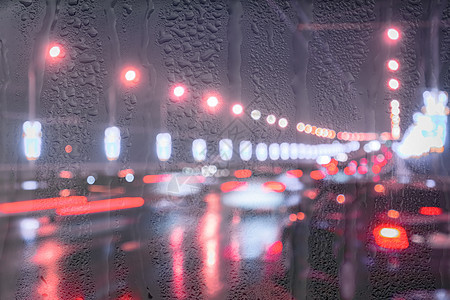 夜城的湿沥青在雨天窗户后面反射 这些灯光闪烁着汽车和灯笼路灯运输背景夜生活场景天气城市运动街道交通图片