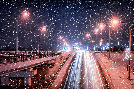 冬季晚上在大桥的雪瀑上行驶的汽车头灯的痕迹 湿沥青中的灯光反射车辆市中心驾驶街道速度运动景观灯笼城市夜景图片