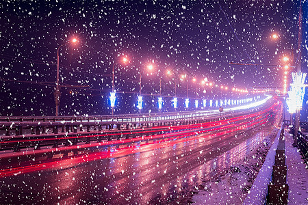 冬季晚上在大桥的雪瀑上行驶的汽车头灯的痕迹 湿沥青中的灯光反射运动大灯速度交通车辆城市景观夜景辉光运输图片