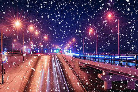 冬季晚上在大桥的雪瀑上行驶的汽车头灯的痕迹 湿沥青中的灯光反射踪迹大灯辉光市中心速度车辆驾驶交通夜景运动图片