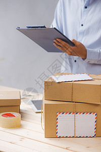 表上各包裹之间在收货中作笔记的送货员商业白色盒子男人送货邮件船运运输邮政命令图片