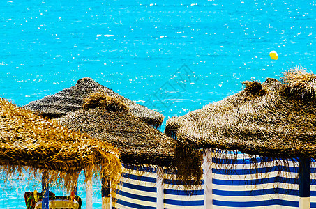 美丽的沙滩 有棕榈树雨伞和蓝海旅游棕榈稻草休息室热带晴天海洋天空游客支撑图片