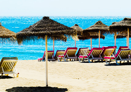 美丽的沙滩 有棕榈树雨伞和蓝海晴天休息室支撑游客阳伞海景情调稻草闲暇海洋图片