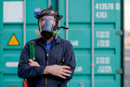 技术员或带化学面具的工人站在绿色容器前拿着扳手 并看起来自信十足图片
