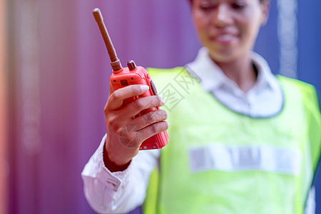 技术员手握着女技师的手 在货物集装箱区持有和展示红色对讲机 并带有良好的沟通概念图片