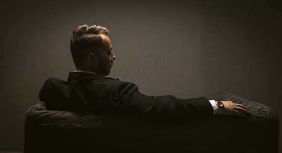 周到的商务人士坐在黑暗房间的沙发上 沉思的优雅男人的背影是孤独的 他的思绪 孤独的概念 领导概念 色调图像图片