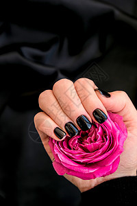 黑钉子修甲把粉红玫瑰花放在黑色丝质织物上 最小的平板性 女性手指甲美容手指奢华表皮凝胶指甲油护理沙龙玫瑰图片