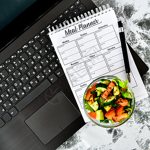 一周的膳食计划 在电脑附近的工作场所用蔬菜沙拉碗 工作间隙在办公室吃午饭桌子食物笔记本营养午餐吃饭学生低热量健康饮食早餐图片
