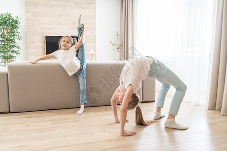 两个女孩在家里的客厅做伸展锻炼行动瑜伽童年身体训练体操闲暇杂技女性女孩图片