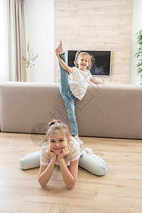两个女孩在家里的客厅里做伸展运动 友好姐妹概念图片