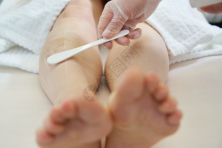 美容学专家为女病人准备在SPA沙龙腿上解开激光发型美容师护理化妆品程序美容皮肤科成人女性诊所温泉图片