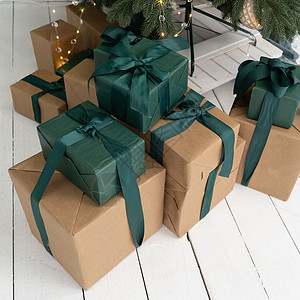 新年礼物就躺在树下 赠品在棕色盒子和绿色包装中 盒装有丝带和弓图片