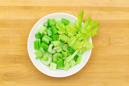 在竹鱼切割板上的白碗中的新鲜切菜切片  最佳视图能源砧板绿色健康饮食芹菜棒生食植物减肥木板食物图片