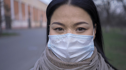 戴面罩的亚洲女人站在户外关上图片