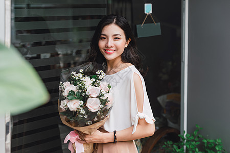 亚裔妇女站在花店里 拿着一束鲜花作品服务花束笔记本女士花朵植物送货玫瑰礼物图片