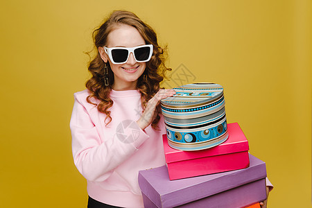 一个快乐的年轻女子 在以橙色工作室背景孤立地购物后 带着彩色纸盒 季节性销售 购买 花钱买礼物幸福购物中心店铺购物狂成人微笑商业图片