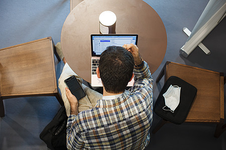 坐在桌子上用笔记本电脑工作的男人的顶端视图男性技术人士经理房间屏幕办公室学生成人商业图片