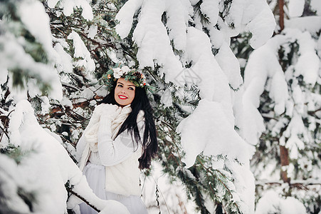 一个穿着白色衣服的女人在寒冷的冬天森林里的画像 在白雪覆盖的冬季森林里 头戴花环的女孩木头裙子艺术帽子雪花季节新年假期镜头新品图片