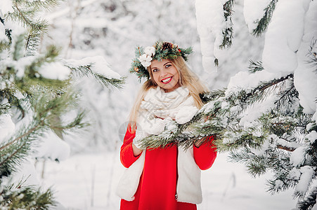 在寒冷的冬季森林里穿着红色夹克的女人的画像 在白雪覆盖的冬季森林里 头戴花环的女孩女士裙子衣服新品花园假期情绪雪花新年帽子图片