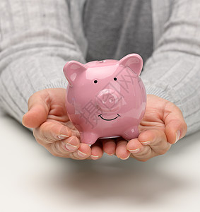 女性手握着一家粉红色陶瓷小猪银行 积累概念 预算控制订金成功会计金融贷款利润货币硬币基金经济图片