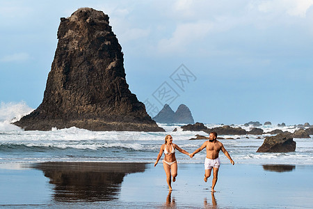 西班牙特纳里夫岛的贝尼霍沙滩上的情侣们蜜月旅行男人海浪女士恋人海岸旅游压痛海景图片